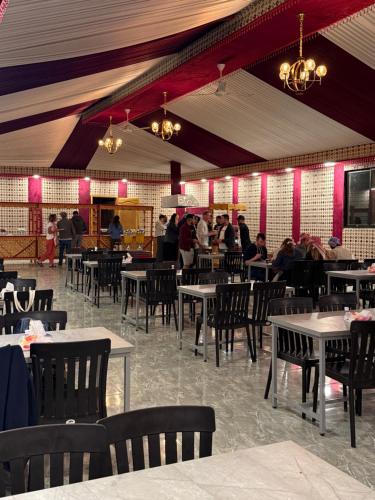 a dining room with tables and chairs and people eating at Ayla Rum Luxury Camp in Wadi Rum