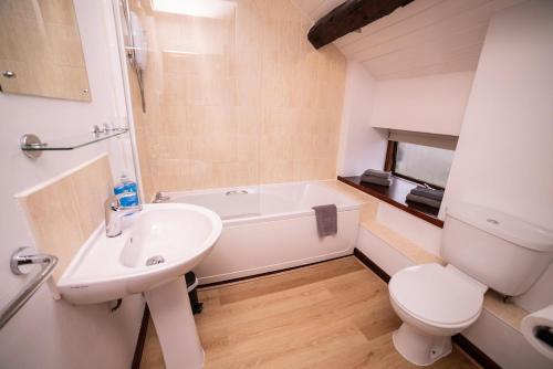 a bathroom with a sink and a toilet and a tub at The Granary in Bampton