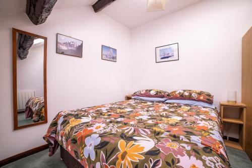 a bedroom with a bed with a floral bedspread and a mirror at The Granary in Bampton