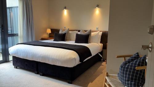 une chambre avec un grand lit avec des oreillers noirs et blancs dans l'établissement Alpine Luxury on London, à Queenstown