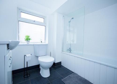 a white bathroom with a toilet and a window at Modern 3-Bed House - Stoke on Trent in Stoke on Trent