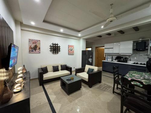Una sala de estar con un sofá y sillas y una cocina. en Platinum Apartment, en Rawalpindi