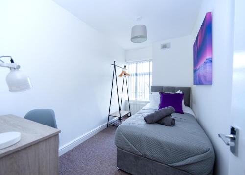 a bedroom with a bed with purple pillows and a sink at Modern 3-Bed House - Stoke on Trent in Stoke on Trent