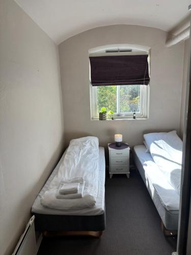 a small room with two beds and a window at Fengselet Gjestegård in Leira