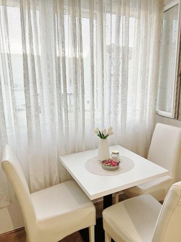 een witte tafel en stoelen met een wit gordijn bij Gold Apartments in Novi Pazar