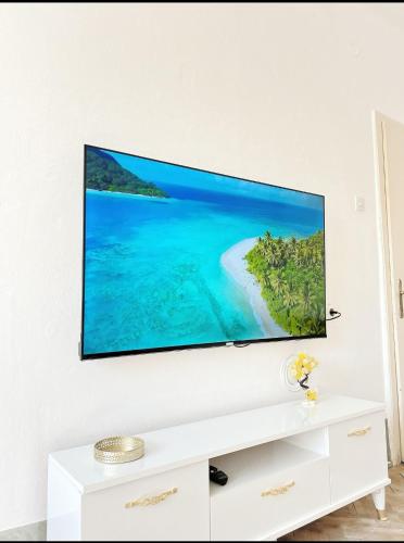 een flatscreen-tv op een witte muur in een woonkamer bij Gold Apartments in Novi Pazar