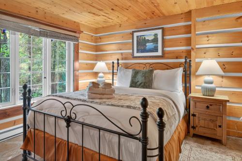 une chambre avec un lit dans une pièce aux murs en bois dans l'établissement Domaine Rivière Sacacomie - Chalet l'Hirondelle, à Saint-Alexis-des-Monts