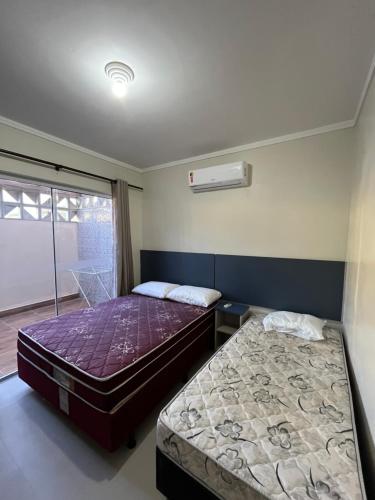 a bedroom with two beds and a window at Miragem de Bombinhas DUO in Bombinhas