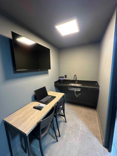 een kamer met een bureau, een laptop en een wastafel bij Kit aconchegante na W3 Norte in Brasilia