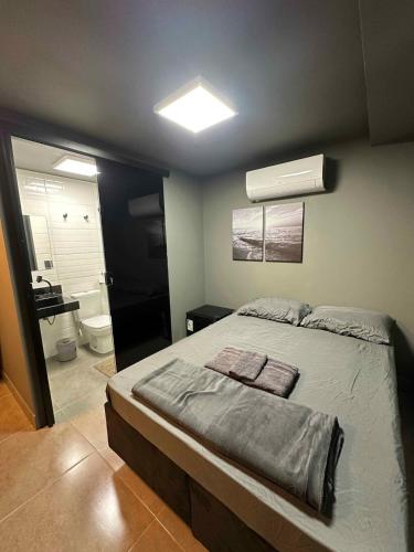 een slaapkamer met een groot bed en een badkamer bij Kit aconchegante na W3 Norte in Brasilia