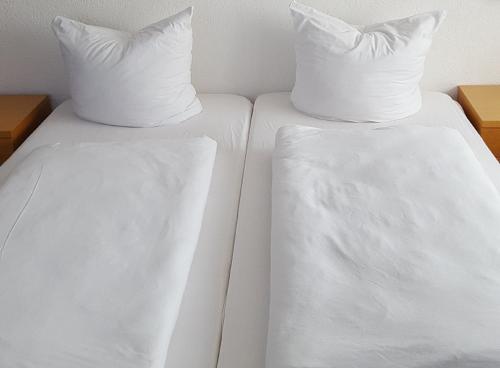two white beds with white sheets and pillows at Hotel M Jacobs GmbH in Gummersbach