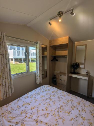 a bedroom with a large bed and a window at Modern Style Pet Friendly Holiday Home sited on Durdle Door Holiday Park in West Lulworth