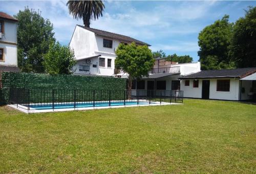 a fence in front of a house with a yard at Casa Amplia 5 personas Con Pileta, Amplio Jardin y Parrilla Zona Muy Tranquila en Tigre Centro in Tigre