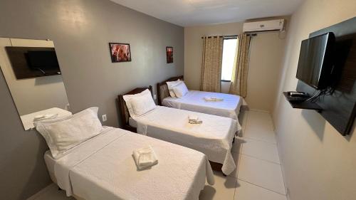 a room with two beds and a flat screen tv at Pousada Marihá in Piranhas