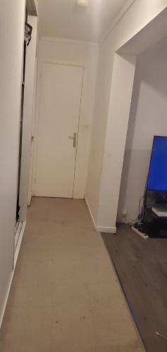 Assurez votre séjour chez Myluck 69 Lyon في بيير - بينيت: غرفة فارغة مع باب أبيض وجهاز تلفزيون