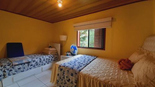 a bedroom with two beds and a window at Refúgio da Colina Lumiar in Nova Friburgo