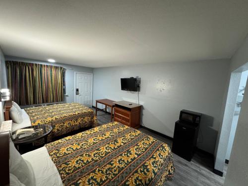 a hotel room with two beds and a flat screen tv at Claremore Motor Inn in Claremore
