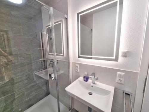 a bathroom with a sink and a shower with a mirror at Ravensburg City Apartment in Ravensburg