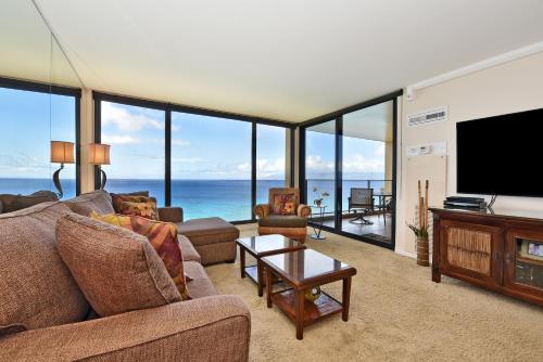 un salon avec un canapé et une télévision à écran plat dans l'établissement Mahana 1217 Oceanfront, à Lahaina