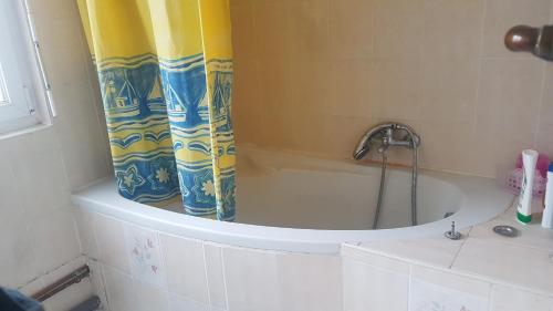 a bath tub with a shower curtain in a bathroom at Chambre in Schiltigheim