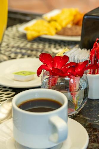 uma chávena de café e um vaso de flores sobre uma mesa em Acamar Beach Resort em Acapulco