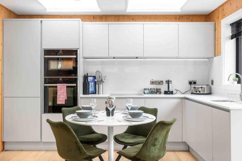 a kitchen with a white table and green chairs at Green Mews 1 with Free Parking By My Getaways in Brighton & Hove