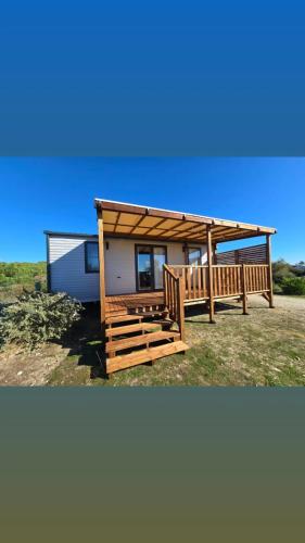 ein kleines Haus mit einer Veranda und einer Terrasse in der Unterkunft Camping le soleil d'or Mobil Home in Montalivet-les-Bains