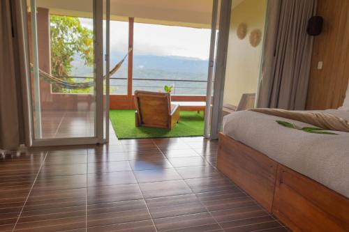 a bedroom with a bed and a balcony with a chair at Vibra Healing Lodge y Spa in Teniente Hugo Ortiz