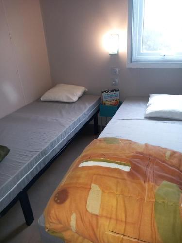 ein Zimmer mit zwei Betten und einem Fenster in der Unterkunft Camping le soleil d'or Mobil Home in Montalivet-les-Bains