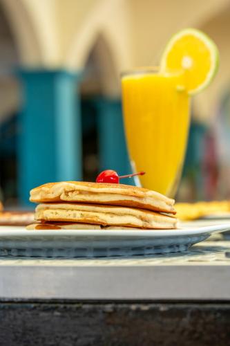uma pilha de panquecas num prato com um copo de sumo de laranja em Acamar Beach Resort em Acapulco