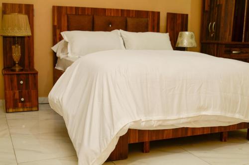 - une chambre avec un grand lit et une couette blanche dans l'établissement Villaggio Budu Room 1, à Weija