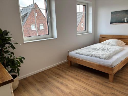 a white bedroom with a bed and two windows at Premium Landhauswohnung in Neuenkirchen