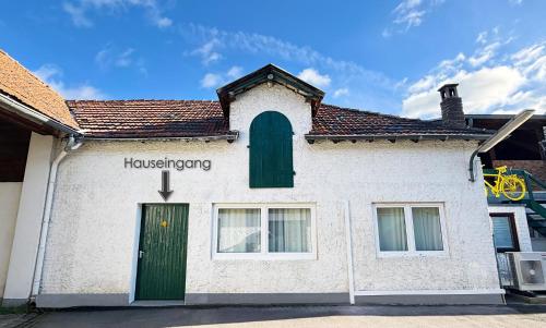 a white building with a green door and a window at Bienenhaus in Troisdorf