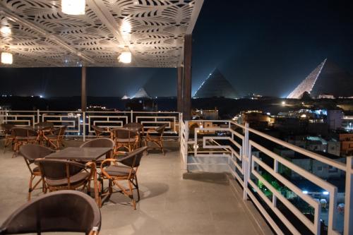 a rooftop patio with tables and chairs at night at Pyraking Pyramids View Hotel in Giza