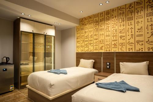 - une chambre avec 2 lits et un mur orné d'une fresque murale dans l'établissement Pyraking Pyramids View Hotel, à Giza