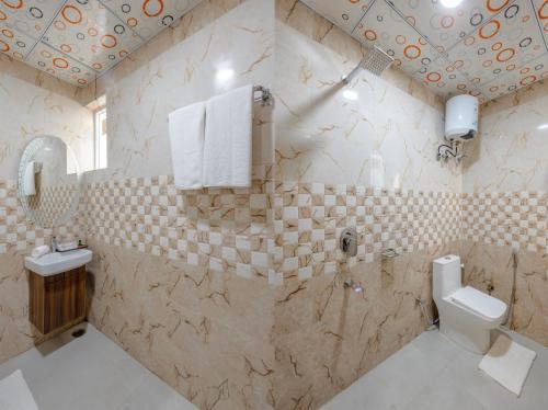 a tiled bathroom with a toilet and a sink at Honeyveils Palace Hotel - Behind Indian Expo Mart in Greater Noida