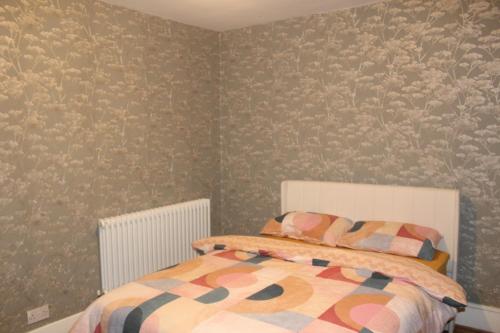 a bedroom with a bed and a wall with wallpaper at Private Room in a Modern Victorian Style House in Chatham