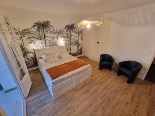 a bedroom with a bed and two chairs at Résidence des îles - Samos III in Ajaccio
