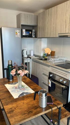 a kitchen with a wooden table with flowers on it at Departameto comodo Coquimbo HA in El Cerrillo