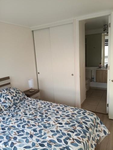 a bedroom with a bed with a blue and white comforter at Departameto comodo Coquimbo HA in El Cerrillo