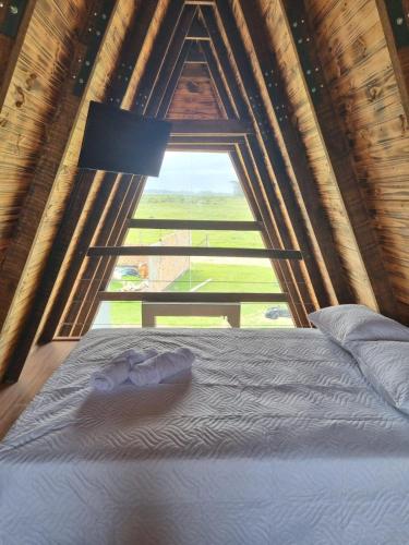 un lit dans une chambre avec une grande fenêtre dans l'établissement Cabana da praia, à Rio Grande