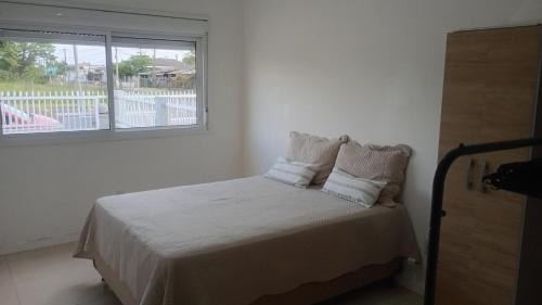 Short stay Osório في أوسوريو: غرفة نوم بها سرير بملاءات بيضاء ونافذة