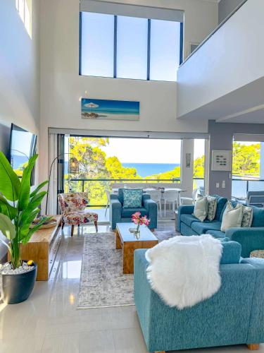 a living room with blue furniture and a large window at Coolum Beachfront Luxury for Family and Friends in Coolum Beach