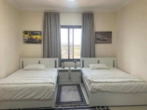 two twin beds in a room with a window at Seaside Two Bedroom Charming Apt in Salalah
