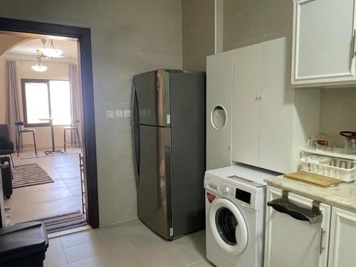 a kitchen with a refrigerator and a washing machine at Seaside Two Bedroom Charming Apt in Salalah