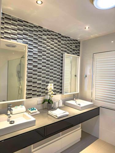 a bathroom with two sinks and a large mirror at Villa Essencia - Luxurious 4br, Gated, Private, Pool in Coolum Beach