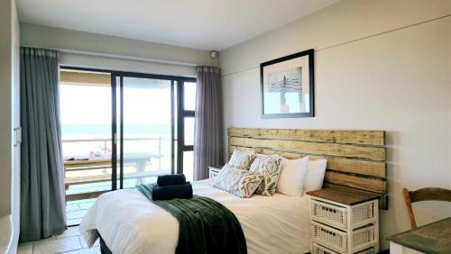 a bedroom with a bed with a view of the ocean at Paradise Beachfront Apartment in Jeffreys Bay