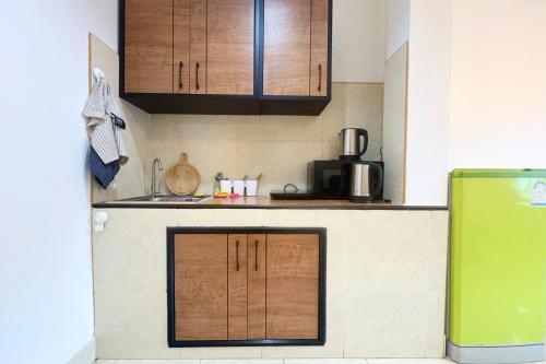 a kitchen with wooden cabinets and a green refrigerator at P&I Group Karon Beach Room-1 in Karon Beach