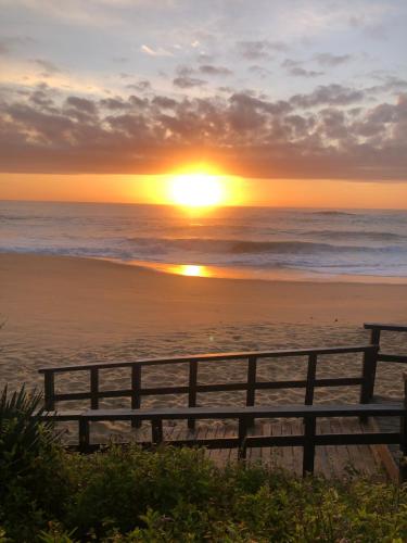 a sunset on the beach with a bench at Estaleiro Casa Hotel in Balneário Camboriú