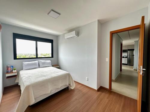 ein Schlafzimmer mit einem weißen Bett und einem Fenster in der Unterkunft Apto Moderno com 2 quartos em Londrina in Londrina